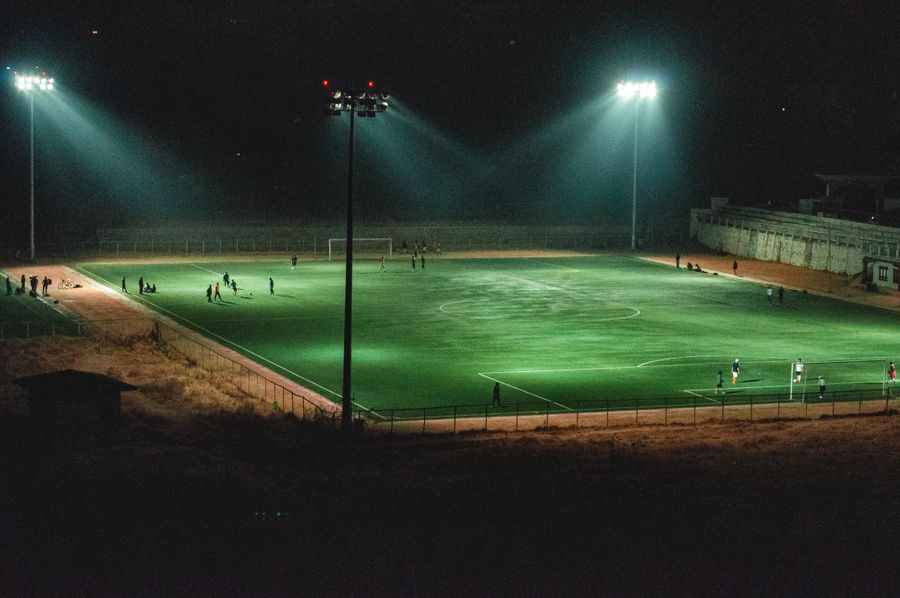 Partido de fútbol nocturno en estadio iluminado